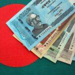 Bangladeshi taka notes lie on Bangladesh flag close up