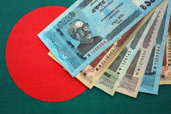 Bangladeshi taka notes lie on Bangladesh flag close up