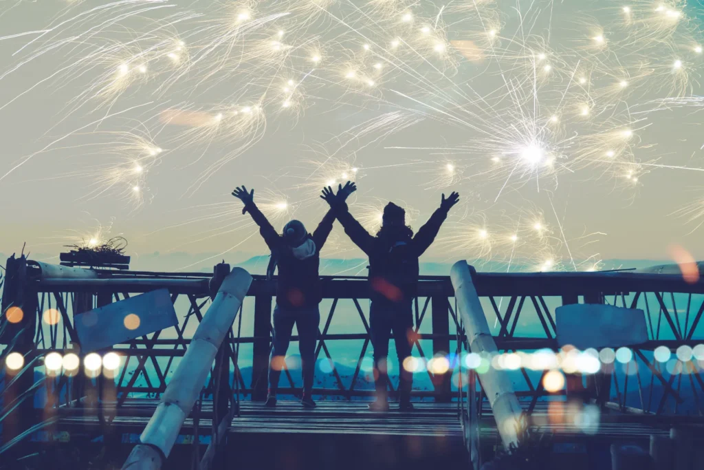 two people with their hands up enjoying the fireworks
