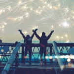 two people with their hands up enjoying the fireworks