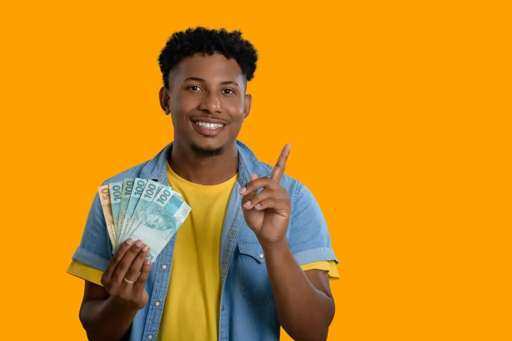 Smiling young man holding Brazilian currency