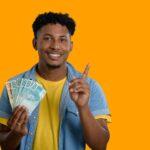 Smiling young man holding Brazilian currency