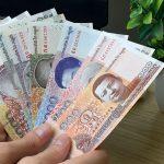 A man holds Cambodian riel banknotes of various denominations.