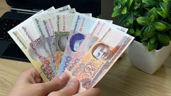 A man holds Cambodian riel banknotes of various denominations.