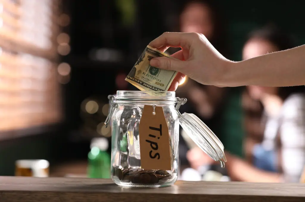 Woman putting tips into glass jar
