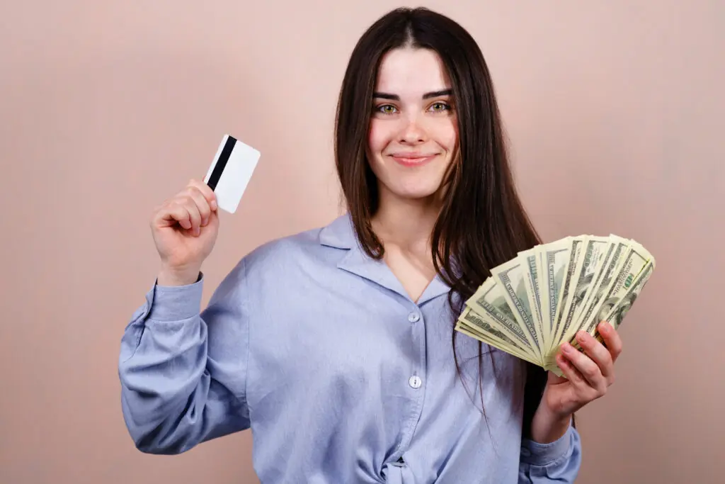 Young happy cheerful woman with credit card and dollar bills