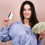 Young happy cheerful woman with credit card and dollar bills