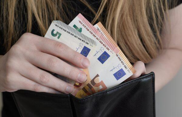 Young woman putting euro money into her wallet